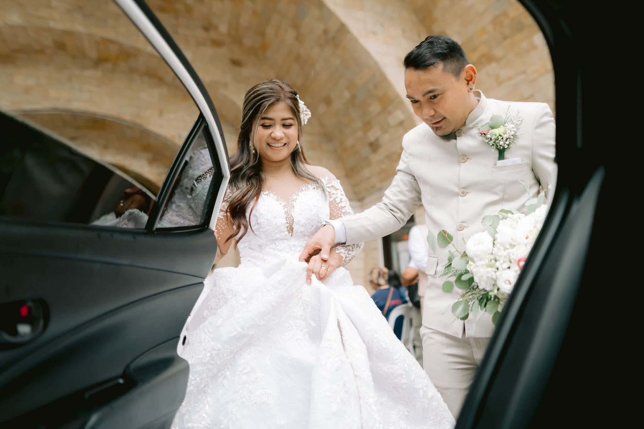A groom helping his bride into the car bound for the reception