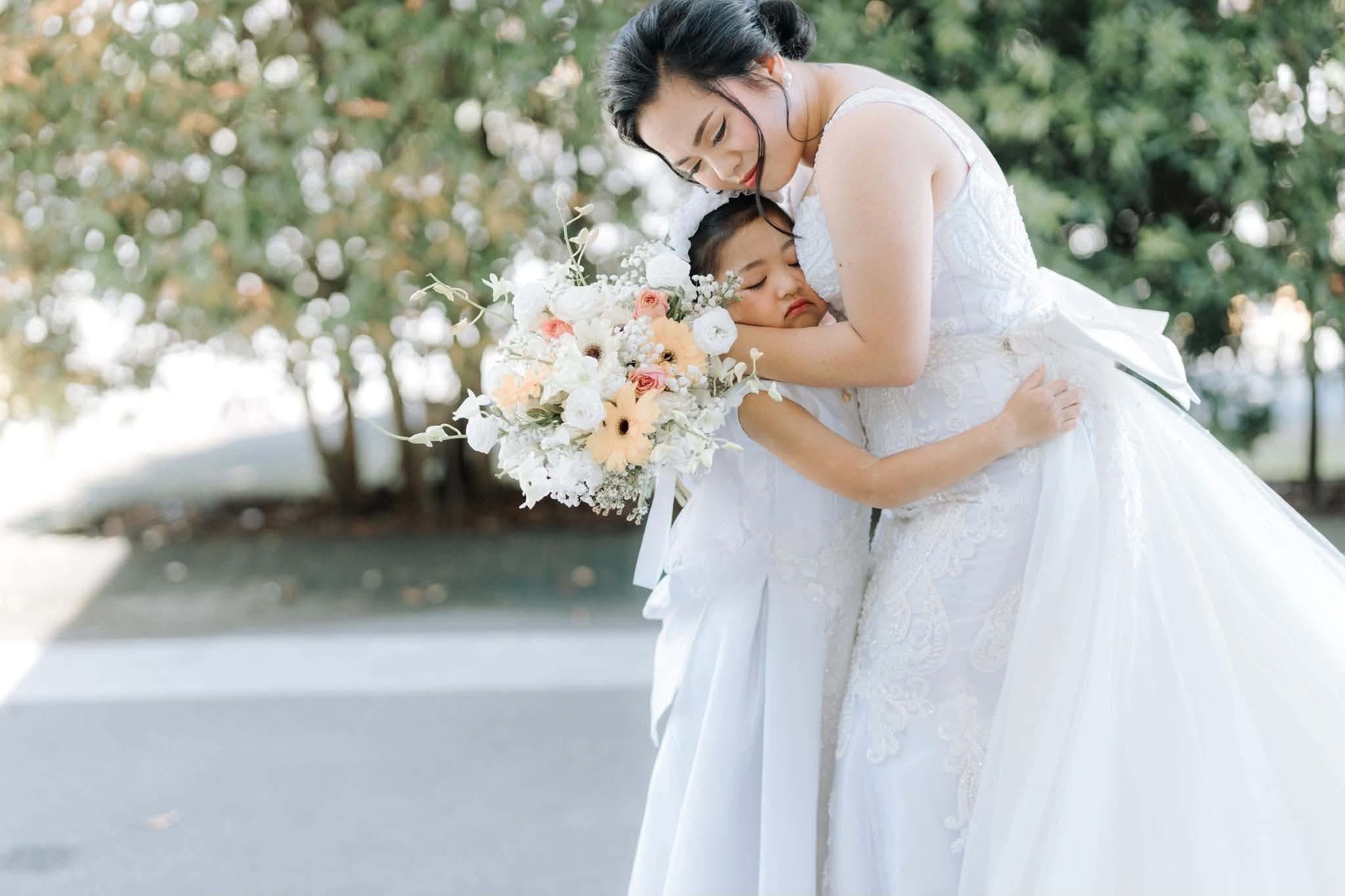 A bride embracing a sleepy flower girl