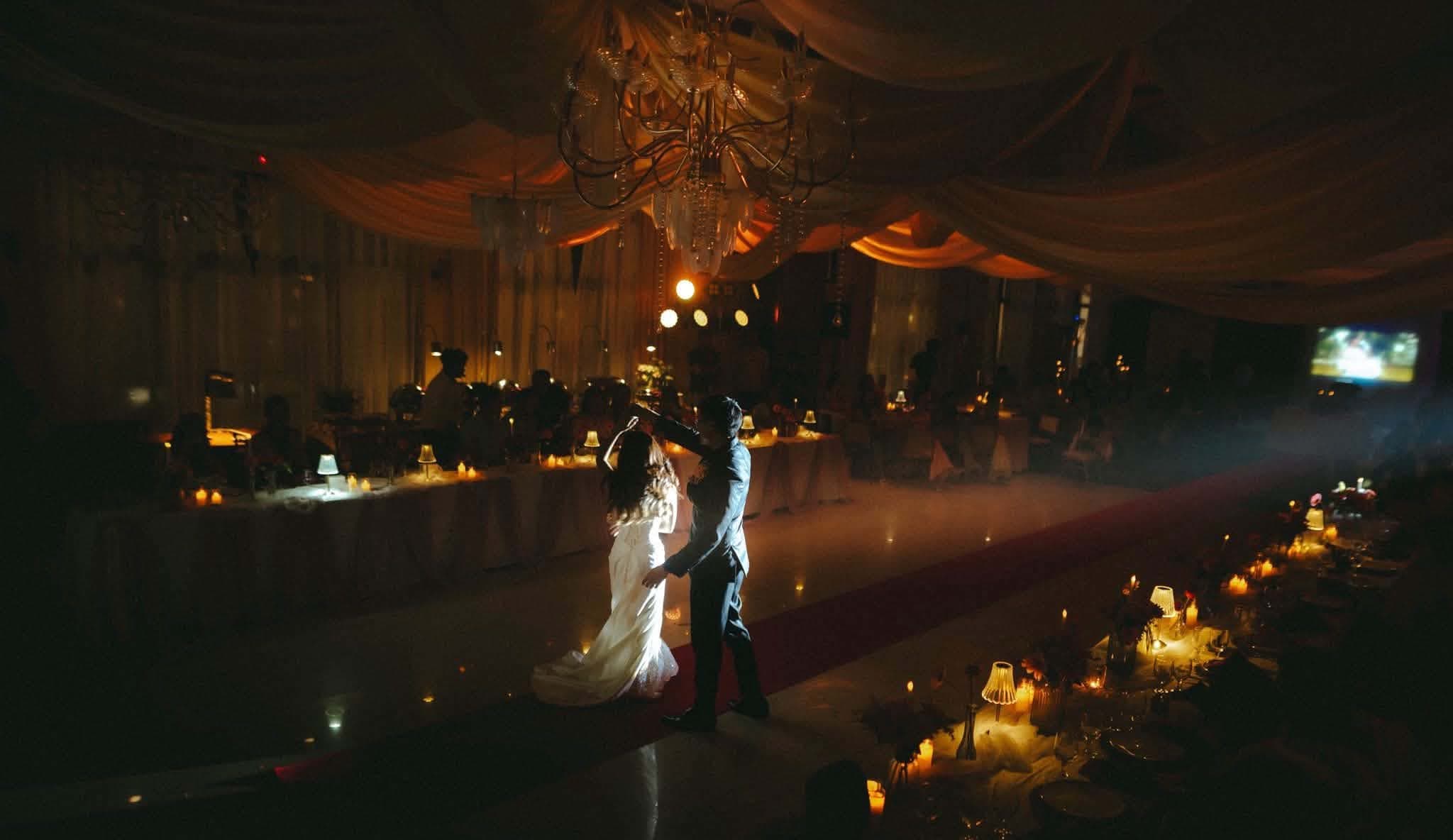 A wide candlelit ballroom during the couple's first dance
