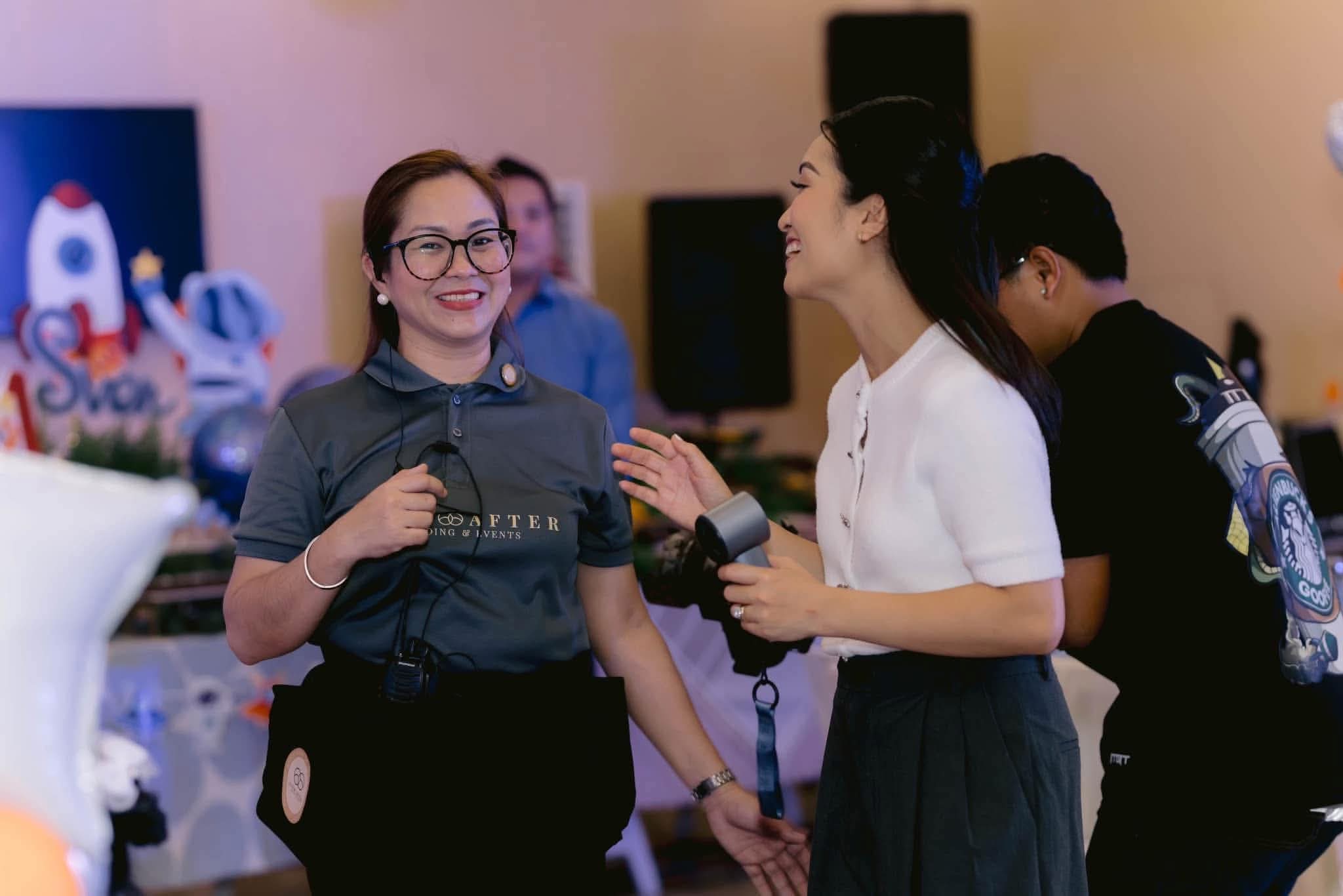 A coordinator in a branded polo with a radio at her waist talking with a client in a decorated function room
