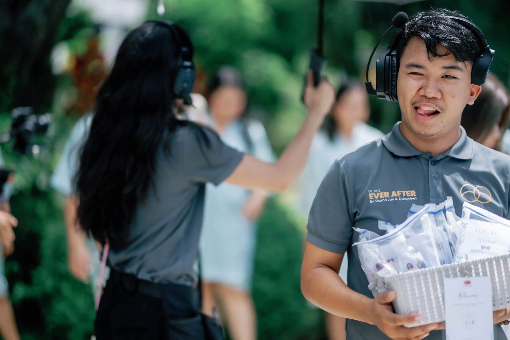A coordinator in a branded polo and headset carrying a basket of labelled kits for the entourage
