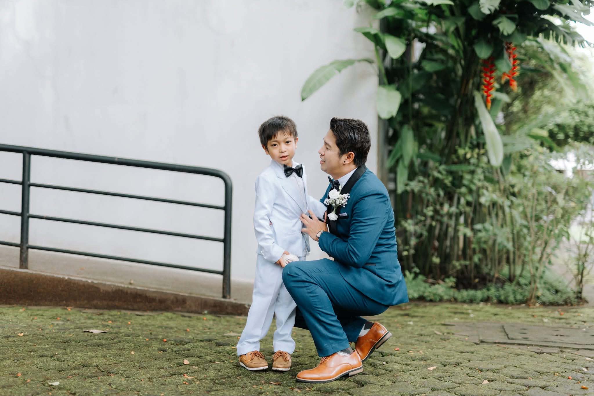 A groom crouching to talk with the young ring bearer