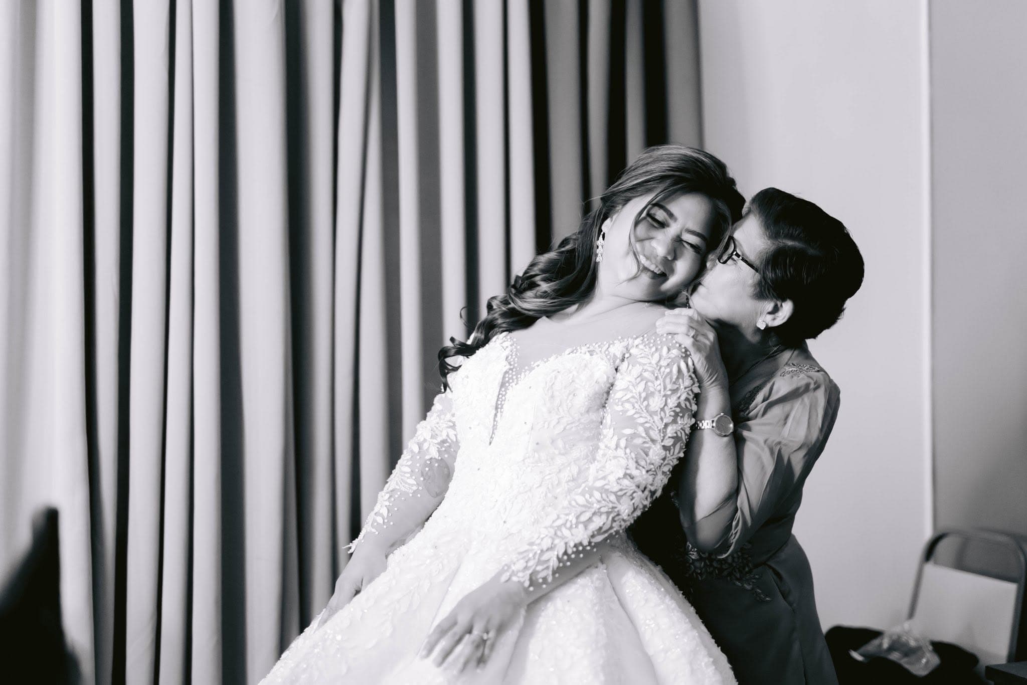 A bride held in her mother's arms before the ceremony, in black and white