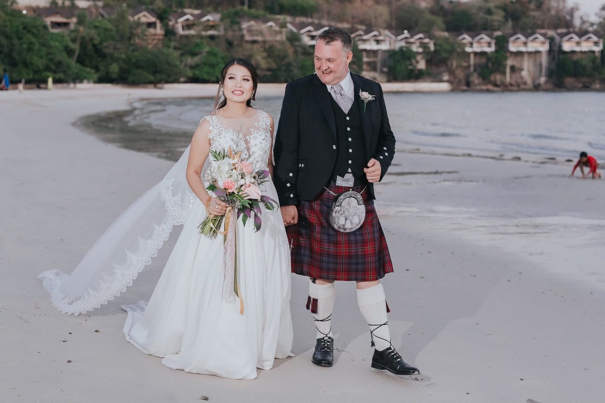 Newlyweds walking together on a beach at the end of the afternoon