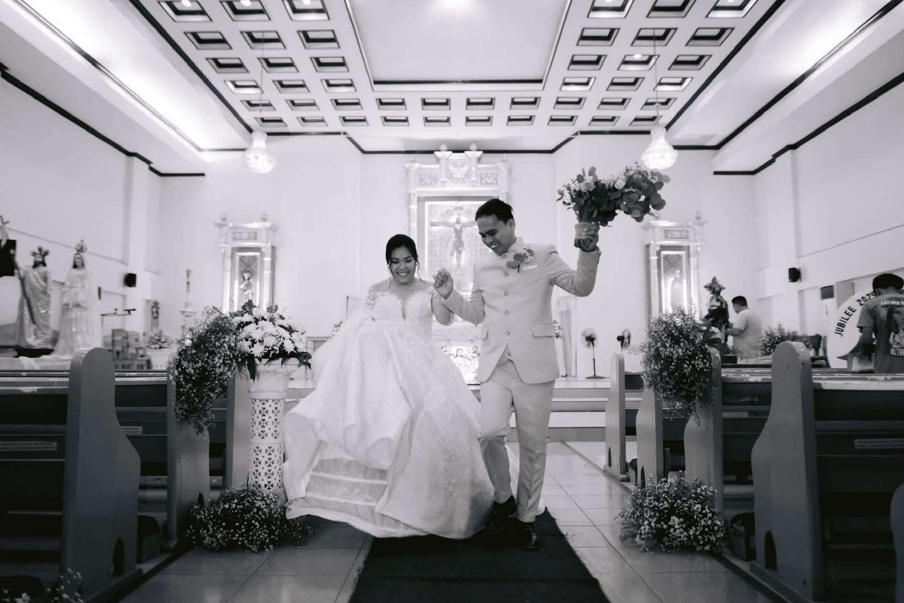 A newly married couple down the aisle with the bouquet raised