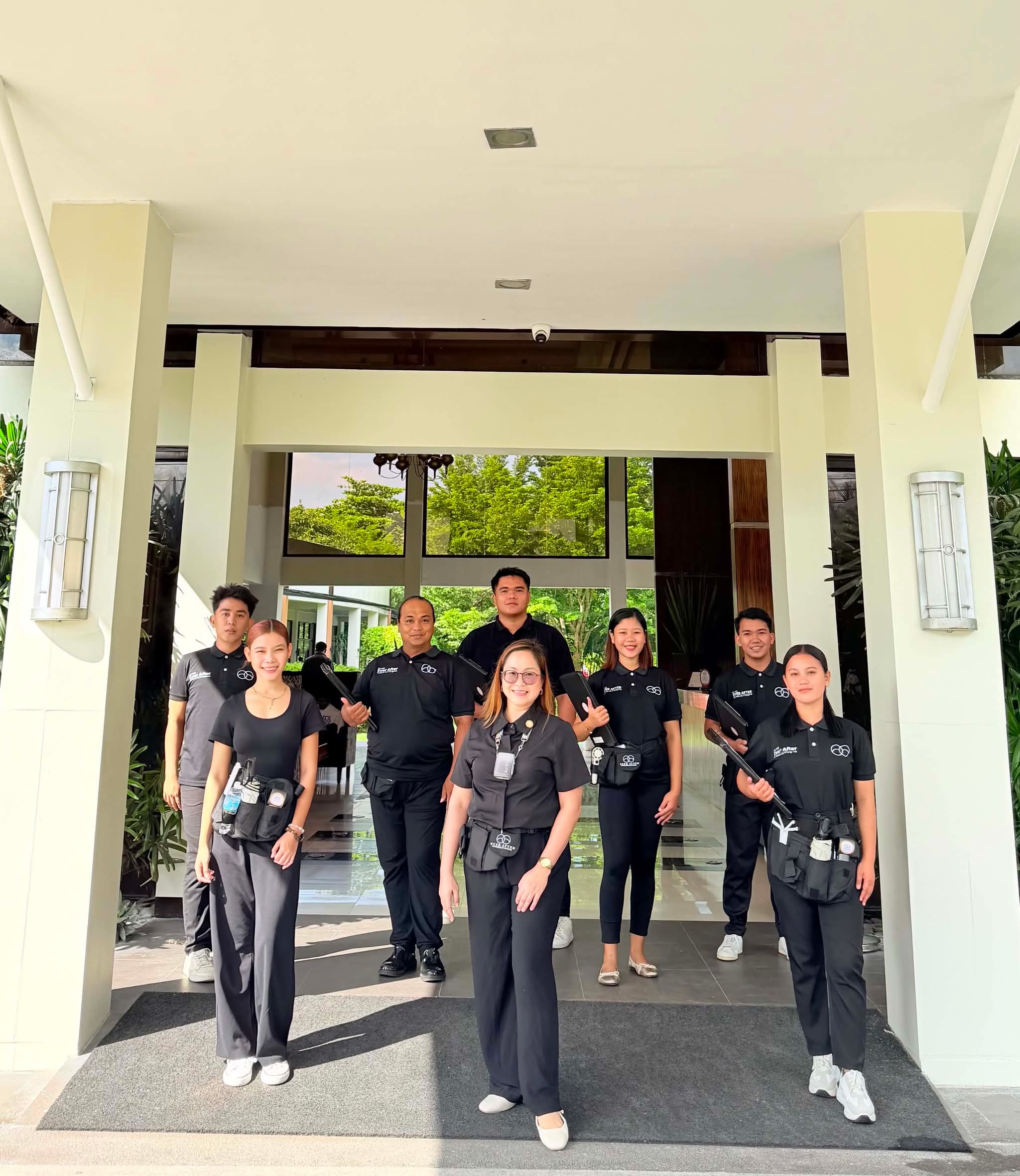 The Ever After team of eight in black on-the-day uniform at a venue entrance, Sharon at the centre